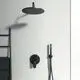 Schwarze Duscharmatur von Ideal Standard, bestehend aus Kopfbrause, Handbrause inklusive Schlauch und Wandmontage, an einer hellen Wand mit Handtuchhalter.